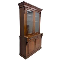 Victorian mahogany bookcase on cupboard, projecting cornice over two glazed doors and carved corbels, fitted with two drawers and double cupboard, plinth base