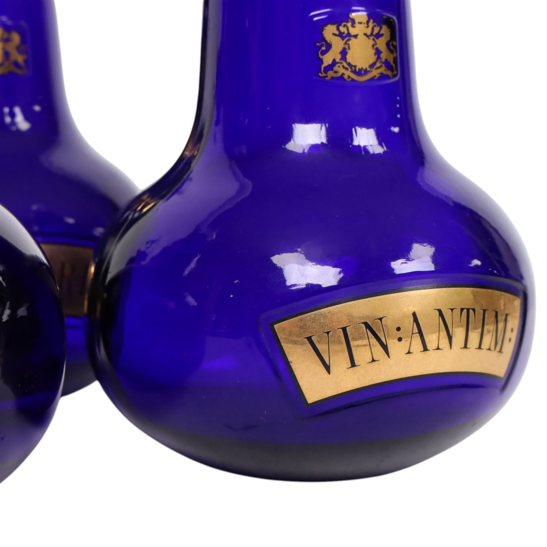 Set of four 20th century Royal Pharmaceutical Society blue glass bottles, of bellied form with clear cut glass spire stopper, each body bearing gilt label in Latin: VIN:ACET:, VIN:ANTIM:, VIN:XERIC:, and VIN:FERR:, and gilt Royal Pharmaceutical Society crest to neck, H25cm

Provenance: From the collection of the family of Peter Green, a practising pharmacist whose career spanned the mid to late 20th century. During his professional life he managed pharmacies in Yeovil, Somerset, and later Selles Chemist in Filey, North Yorkshire, before purchasing and running his own business, Peter Green Pharmacy, located in the Market Place, Malton. The bottles were displayed as part of the traditional shop fittings in both the Filey and Malton pharmacies and were retained as part of his collection.