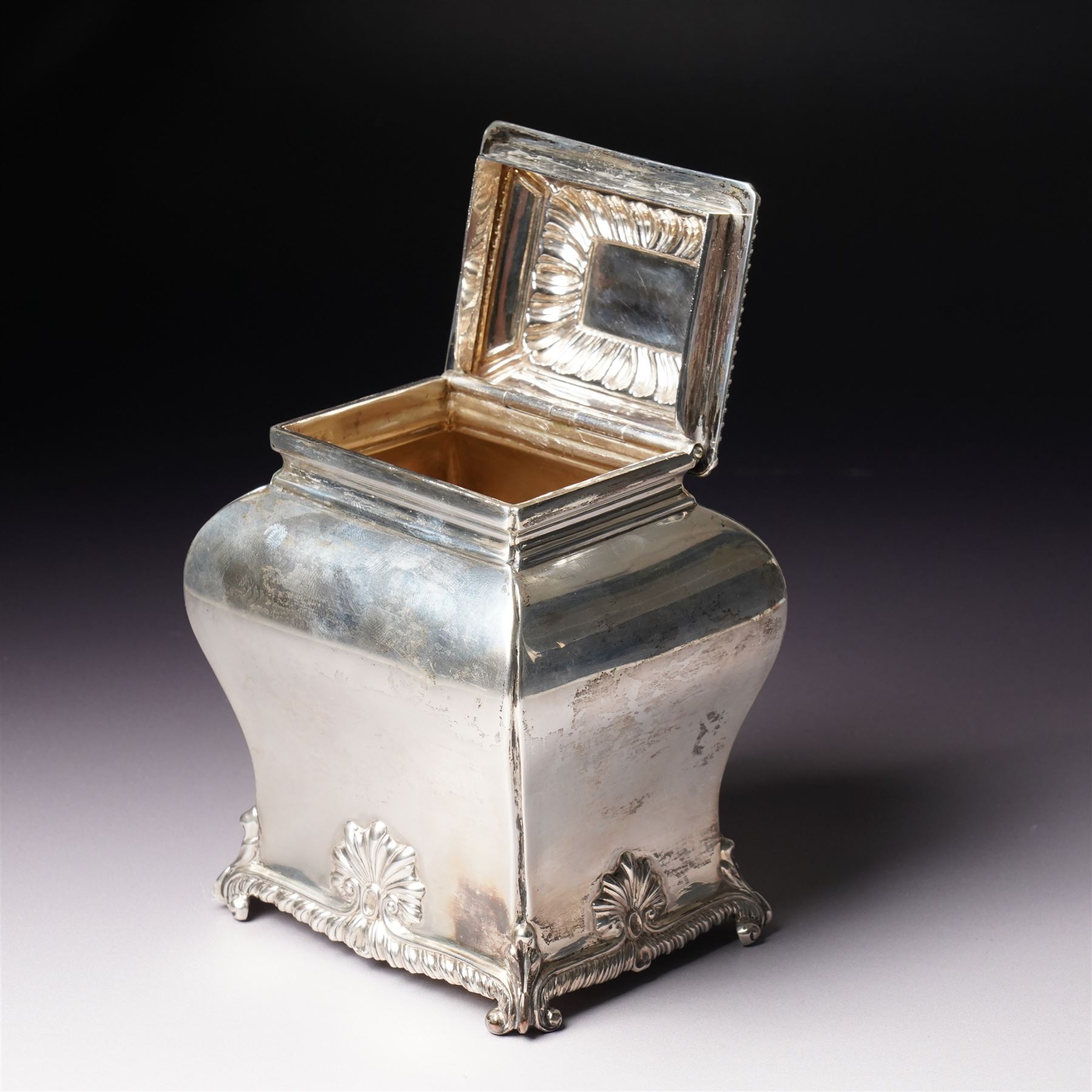 Edwardian silver tea caddy of bombe outline with shell moulded finial, shell moulded and gadrooned base on scroll feet H15cm London 1902 Maker Thomas Bradbury & Sons