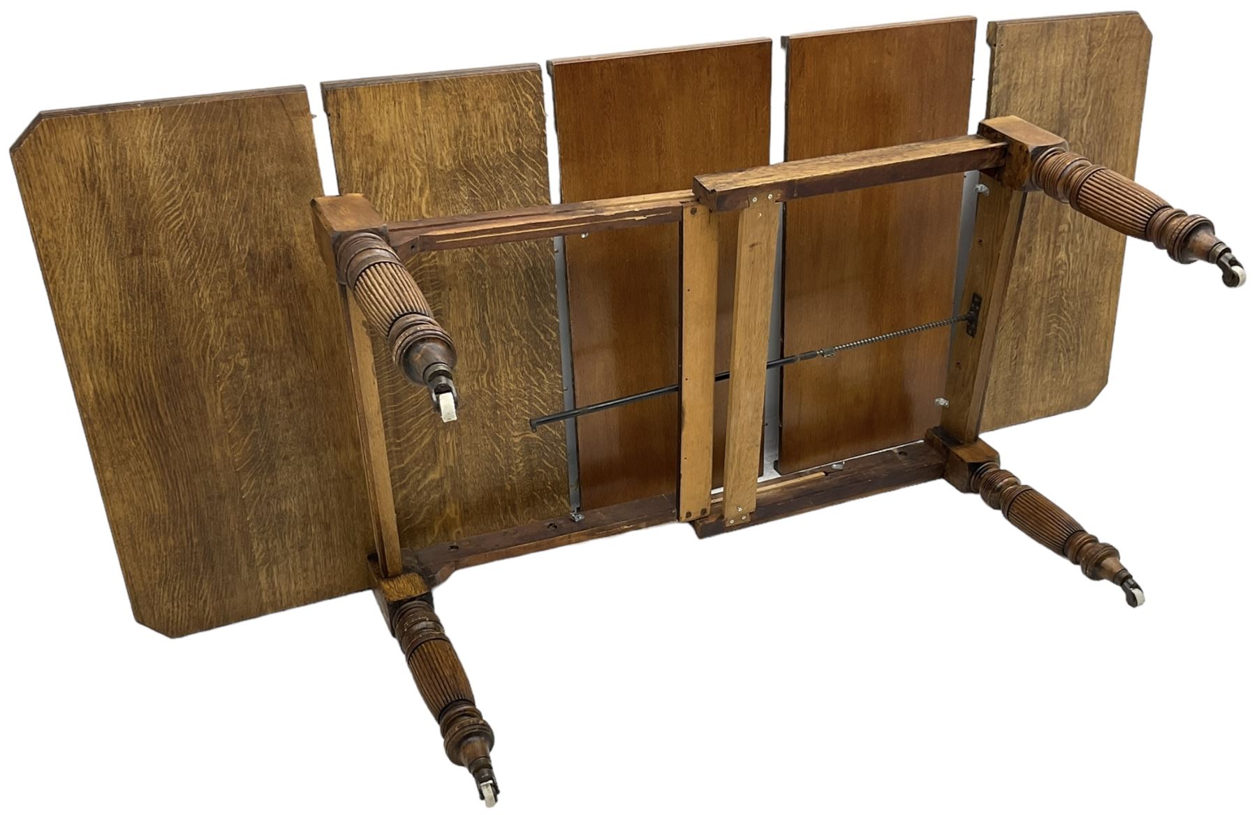 Late Victorian oak telescopic extending dining table, rectangular moulded top with canted corners, three additional leaves, on turned and reeded supports with brass and ceramic castors