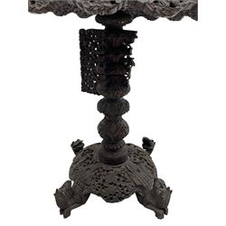 Late 19th century Anglo-Indian carved hardwood occasional table, circular tilt-top carved profusely with mythical animals and foliage decoration, pierced and carved with interlaced leafy branches, leaf carved pedestal supports on a raised platform with further carved and pierced foliage decoration, four carved feet in the form of mythical beasts with gaping jaws 
