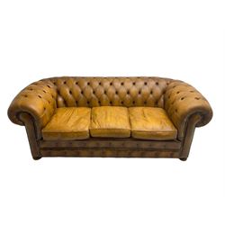 Chesterfield three seat sofa, upholstered in buttoned tan leather with studded detail, on turned feet