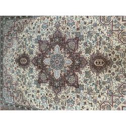 Persian Heriz ivory ground rug, central geometric rosette medallion on field of interlacing foliage and stylised flower heads, repeating guarded border with signature panels