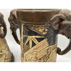 Pair of Bretby vases of tapering cylindrical form decorated with elephants, cranes and fishermen, the bodies with twin elephant mask handles, with coppered borders, raised upon three bun feet, stamped Bretby 2246 marks beneath, H32cm