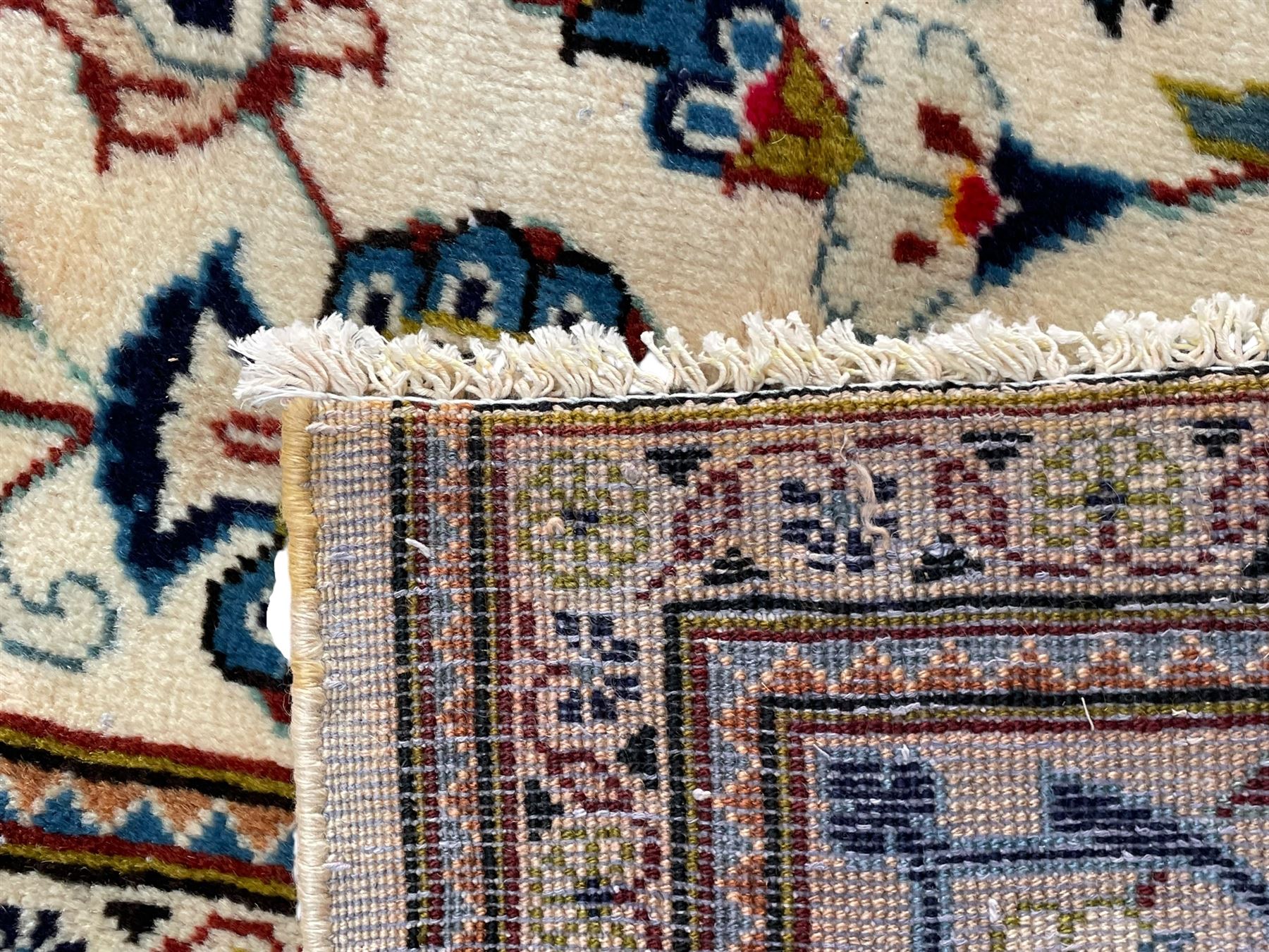 Persian Kashan ivory ground carpet, the field decorated with scrolling branches with foliate and palmette motifs, repeating border with stylised plant motifs, within floral and geometric pattern guard stripes 