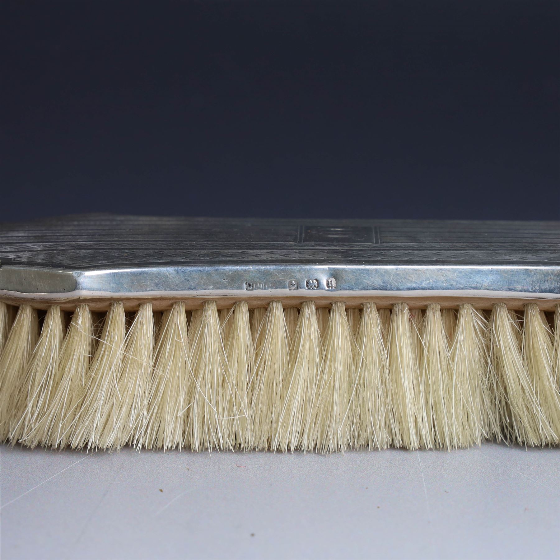 Five silver mounted dressing table items, including 1920s mirror and hairbrush set, with engraved initial to reverse, pair of clothes brushes with engraved initials and engine turned decoration and an oval clothes brush, all hallmarked 