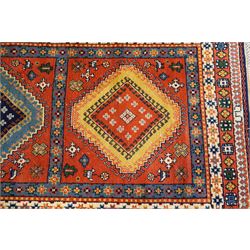 Caucasian Kazak vermillion ground rug, the sectioned field decorated with three geometric lozenge medallions surrounded by stylised plant and animal motifs, the multiple guard bands with repeating geometric design