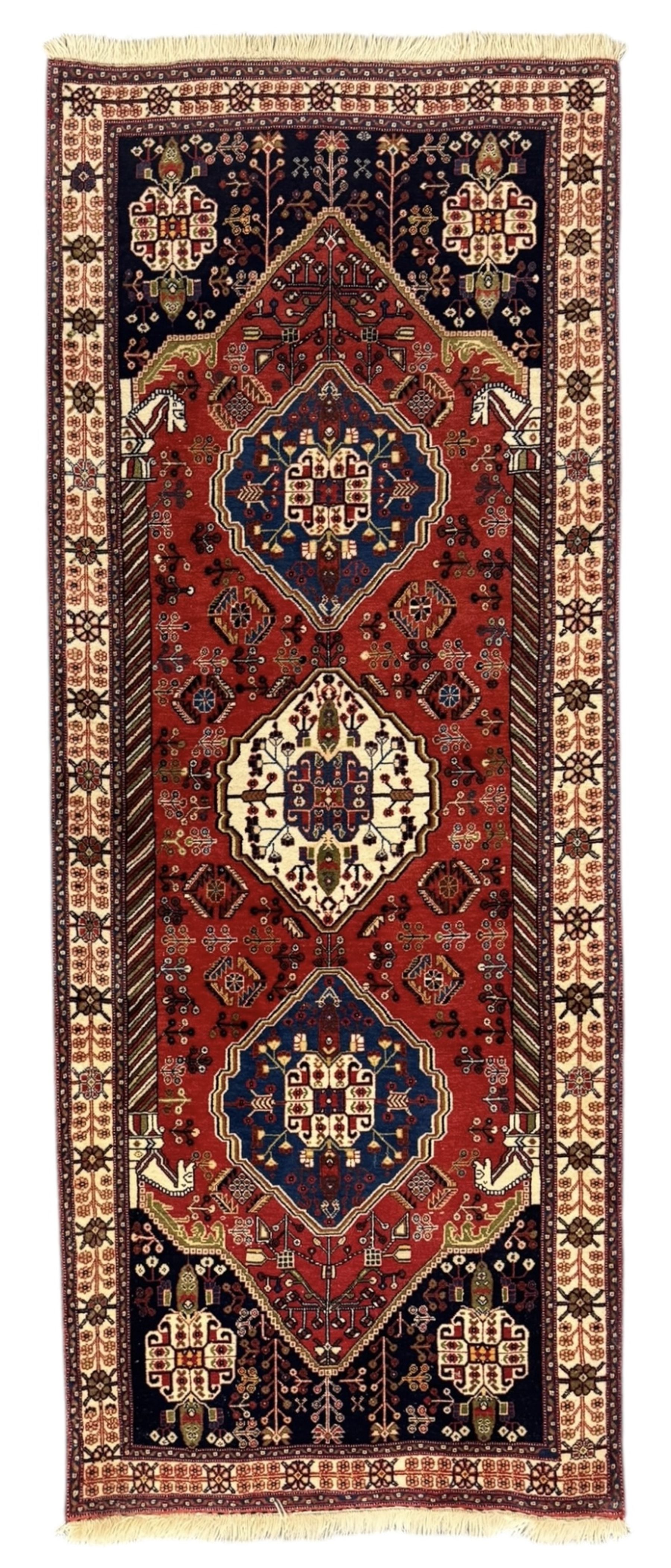 Fine Persian Qashqai crimson and navy ground runner, three large medallions filled with geometric and floral designs, the field with angular vines and stylised floral decoration, wide ivory border decorated with repeating floral and angular motifs