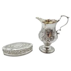 George III silver cream jug, of bellied form with capped scroll handle and embossed foliate decoration, upon a spreading circular foot, hallmarked London, probably 1776, maker's mark worn and indistinct, H11.5cm, together with an Edwardian silver box of elliptical form, with inset coin to the hinged cover and embossed scrolling foliate decoration throughout, hallmarked 	Samuel Jacob, London 1901, L10cm, approximate total weight 4.72 ozt (147 grams)