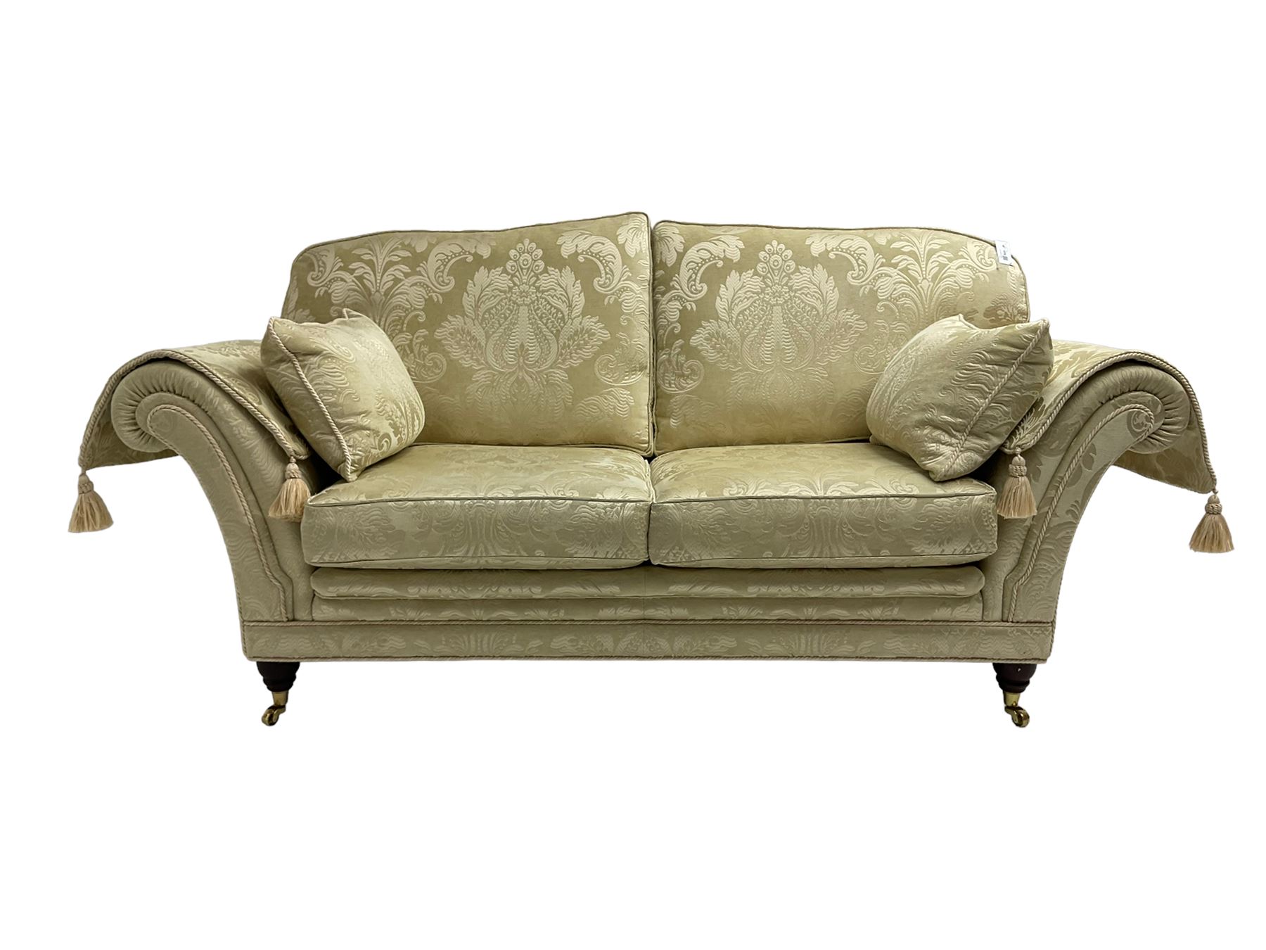 Steed Upholstery - two seat traditional shaped sofa, upholstered in cream fabric with scrolling foliate pattern, on turned front feet with brass castors, with side cushions and arm covers