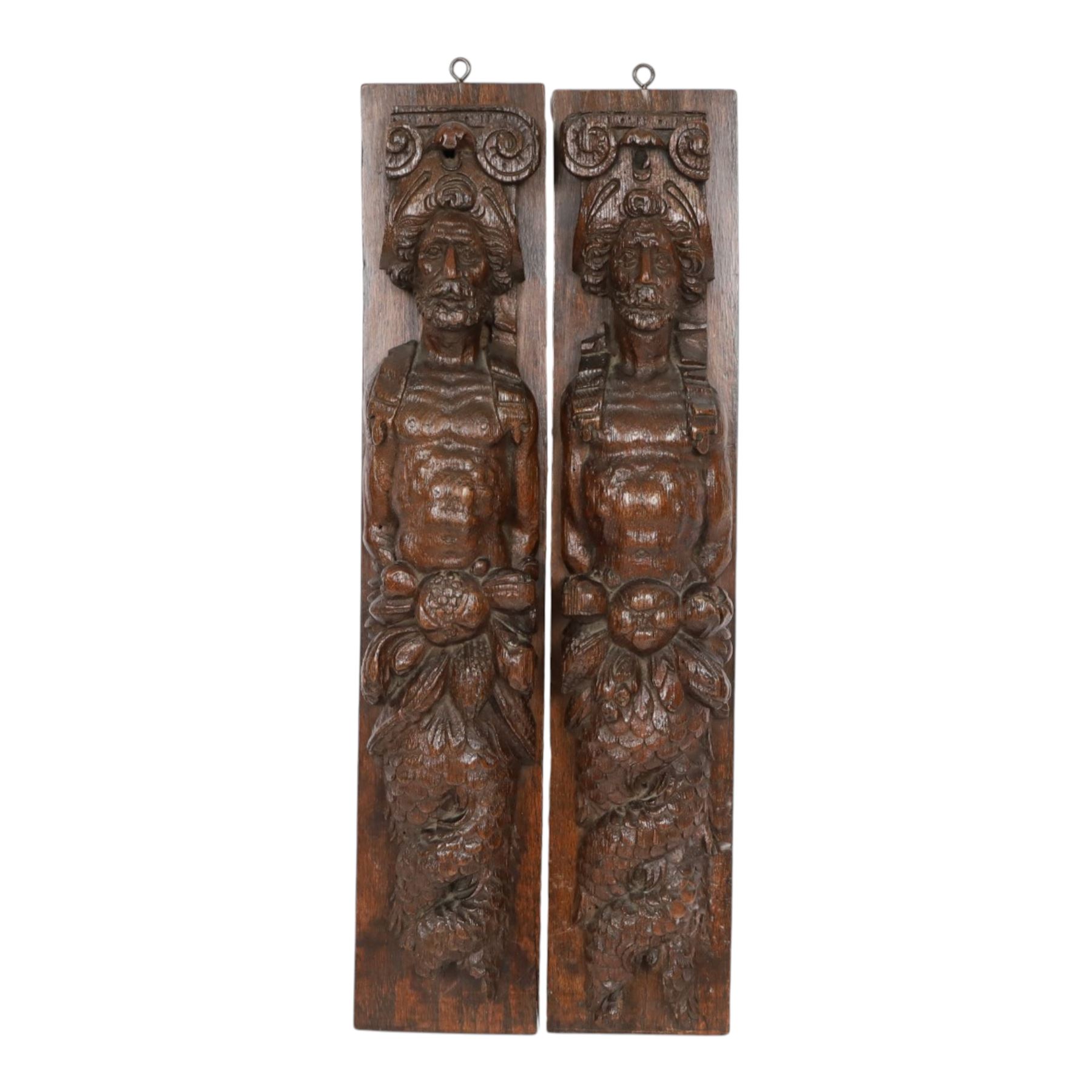 Pair of 17th century carved oak terms, each depicting a male figure in headpiece, with fish tail beneath fruits, 51.5cm