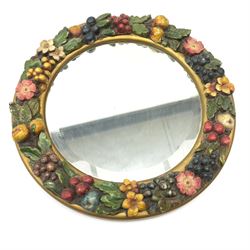 A 20th century circular framed mirror, the frame with painted fruit and flowers in relief, overall D34cm. 
