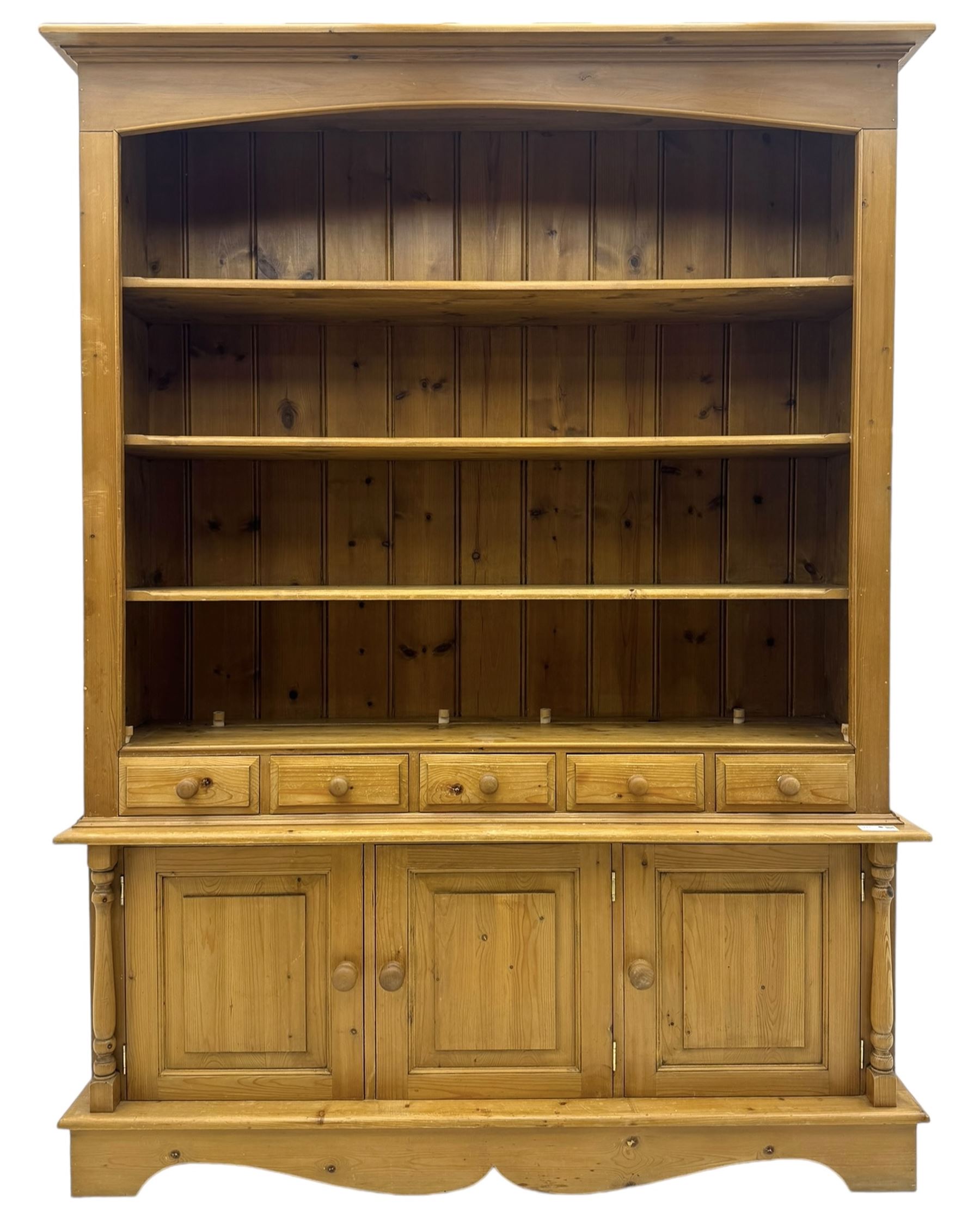 Early 20th century pine kitchen dresser, featuring a hutch with arched top over three open shelves, the base with five drawers over three cupboard doors, turned column supports flanking the doors, scalloped apron base with bracket feet