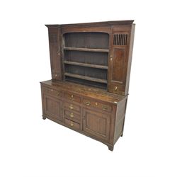 George III oak dresser, projecting cornice over three tier plate rack flanked by reeded uprights and two cupboards, enclosed by slatted and panelled doors above small drawers, the lower section fitted with six drawers and two cupboards, on bracket feet