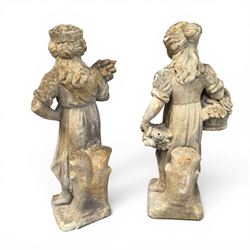 Lucas Stone - pair of cast stone garden figures, modelled as young female figures holding wheat sheafs and baskets of flowers, each on square bases, weathered finish, makers mark stamped to base