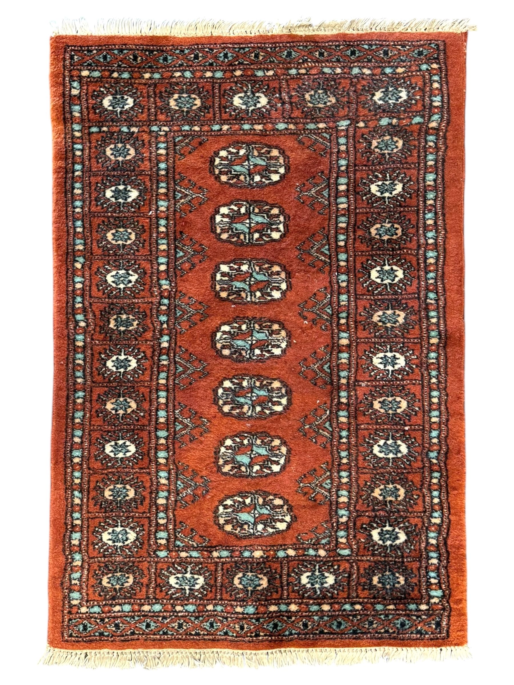 Pair of rugs one Persian hamadan rug central stepped medallion enclosing geometric motifs in ivory and brown, framed by a cream border with scrolling palmettes and fringed ends (H 156cm W 105cm), one Pakistani Bokhara rug rust red ground with repeated Tekke gul motifs within rosette and lozenged borders, fringed ends (H 98cm, W 65cm)