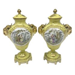 Pair of early 20th century Dresden vases with cover, of baluster form, decorated with figural panels within ornate gilt borders upon a yellow ground, with twin gilt goat mask handles, H16.5cm