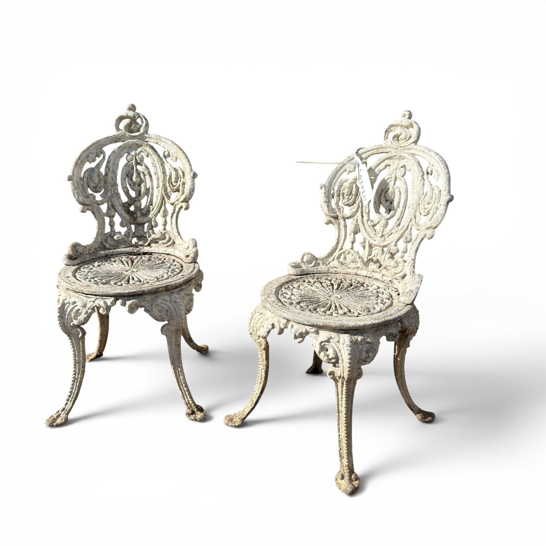Pair of white painted cast metal garden chairs, ornate reclined backs, circular pierced seats on cabriole legs