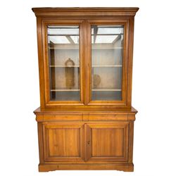 French cherry wood bookcase on cupboard, projecting cornice over two cupboard doors with bevelled glass panels enclosing three adjustable shelves, base fitted with two cushion drawers over double cupboard