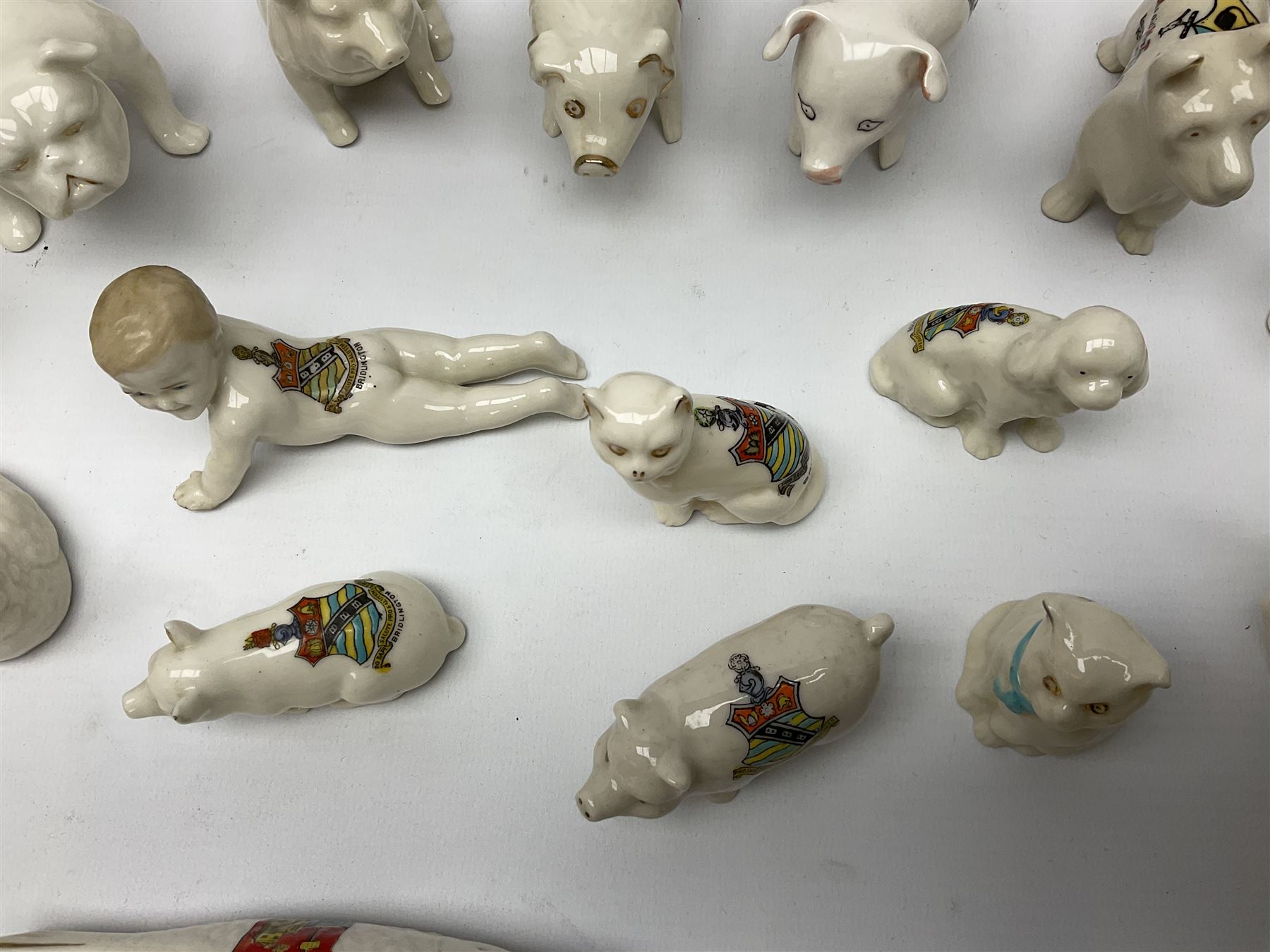 Collection of figural crested ware, to include Carlton Chins John Bull Alnwick, Clifton China Cheshire Cat,  Arcadia pig, Crafton crawling baby and another seated baby, quantity of cat, dog and pig figures, two Willow Art Model of Bunyans Statue, Toby jug, Victoria China, Arcadan bulldog, fish etc