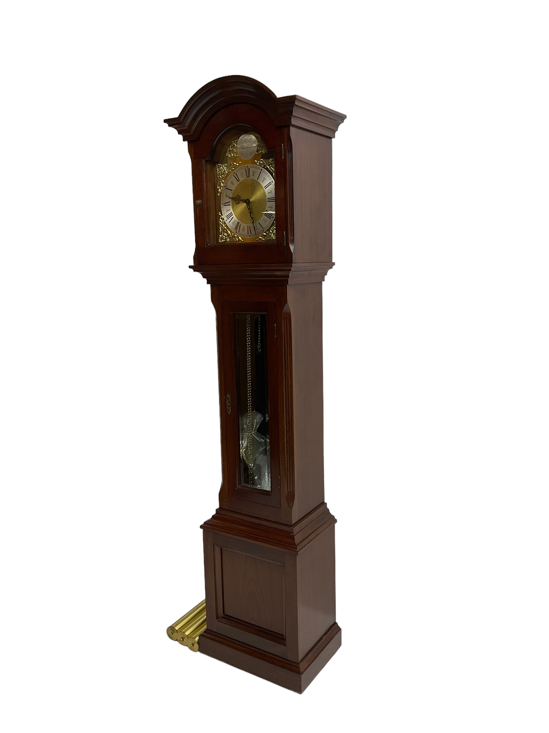 Mahogany cased Grandmother clock c 1980 made and retailed by Julian Stanton, Winchester, with a break arch pediment and corresponding brass dial, full length glazed door displaying three brass cased weights and pendulum, raised on a square plinth with a recessed panel and skirting, German Kieninger three train chain driven movement striking the hours and quarters on 12 gong rods. With weights and pendulum.  