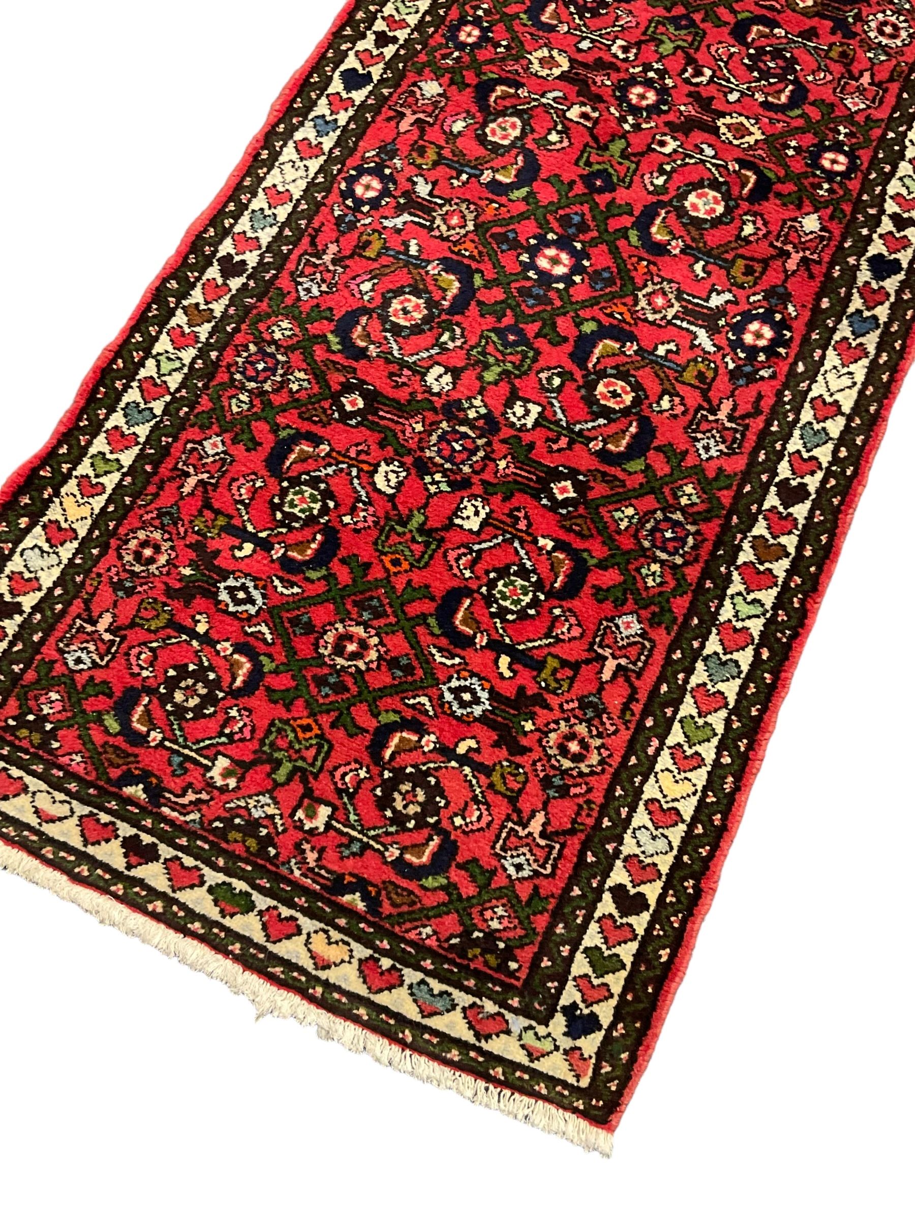 Persian red ground runner, decorated with large Herati motifs and shaped central medallion, the guarded border decorated with repeating heart motifs