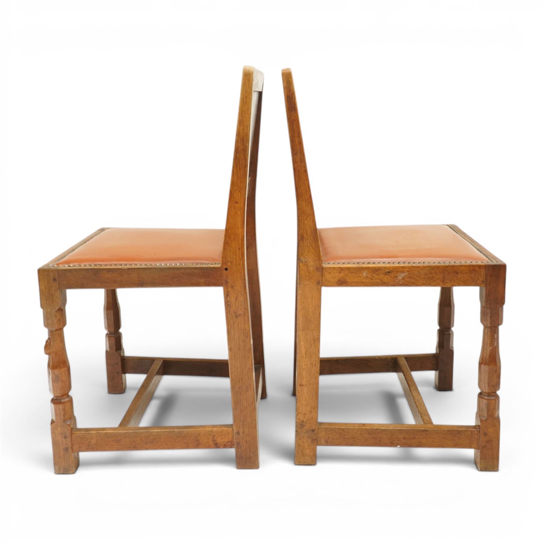 Mouseman - pair of 1940's adzed and panelled oak chairs, the rectangular adzed back-panel over seats upholstered in orange-tan leather with studwork, raised on turned octagonal supports united by box stretcher, with carved mouse signature, by the workshop of Robert Thompson of Kilburn
Provenance: purchased directly from the Kilburn workshop in the late 1940s