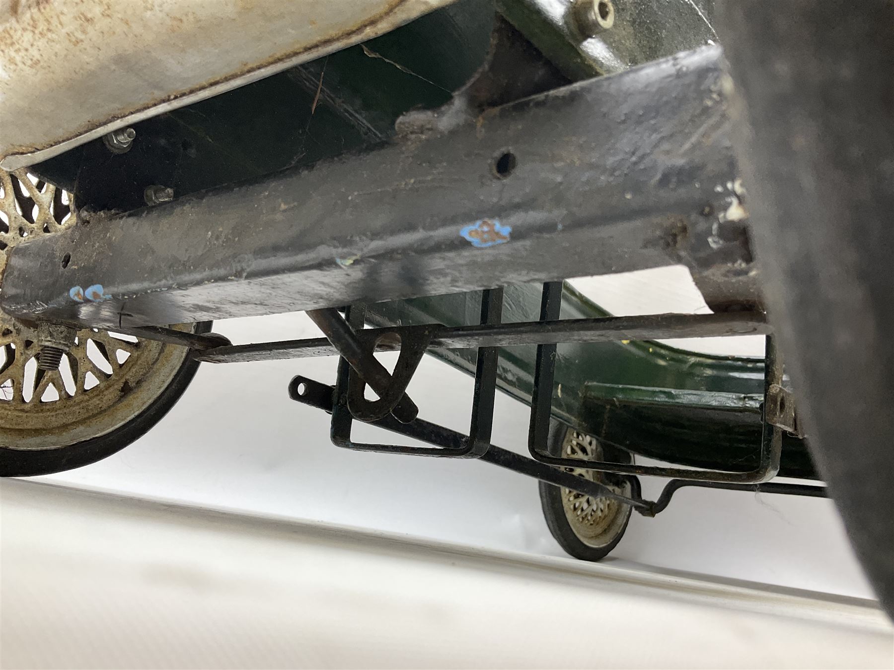 Mid 20th century pressed steel pedal car, the body painted in dark green fitted with pretend radiator to the bonnet, with spoked wheels and rubber tyres, the interior with pedals and steering wheel, L70cm