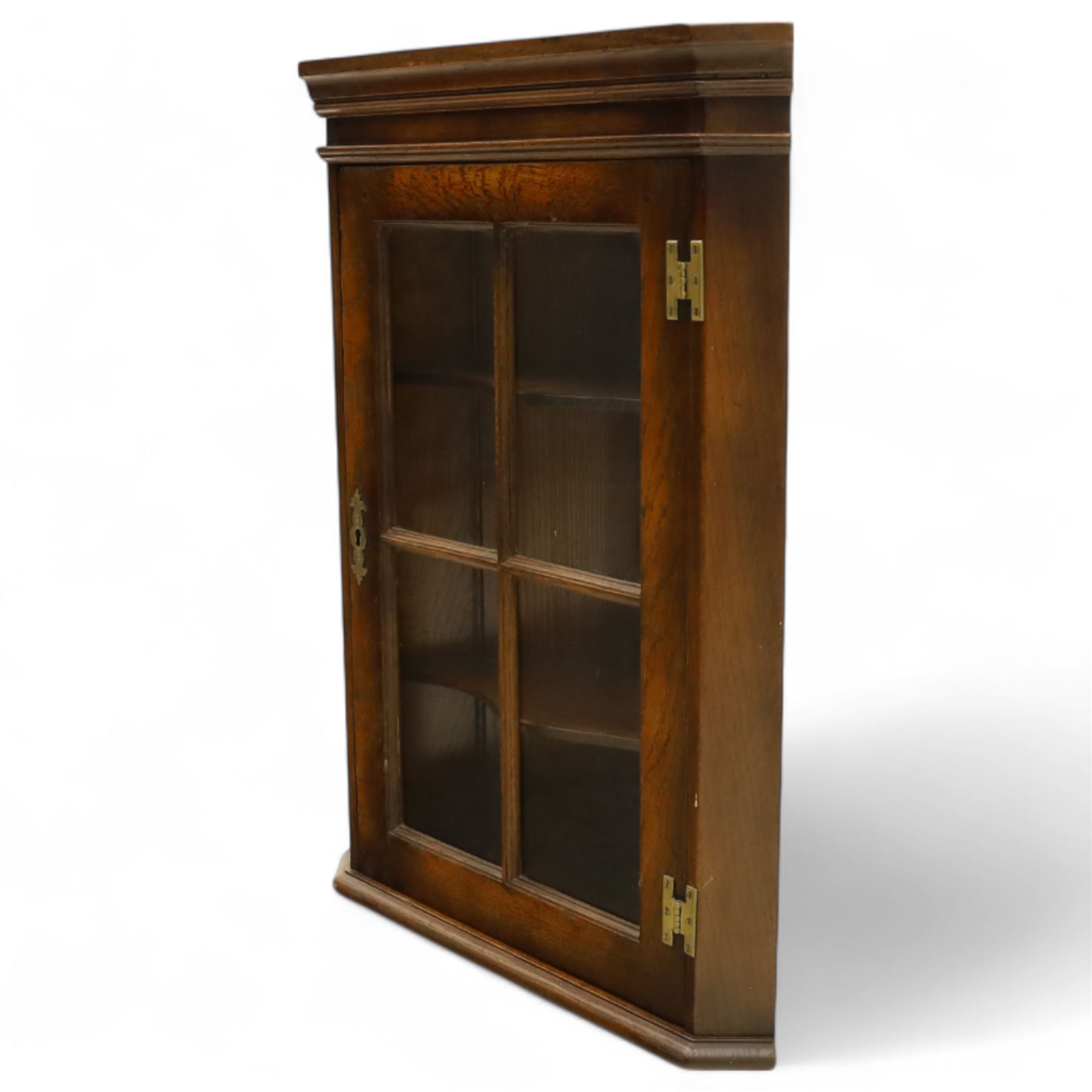 Early 20th century oak wall-mounted corner cabinet, moulded cornice above a single glazed door with six-panel astragal glazing, fitted interior with two shaped shelves