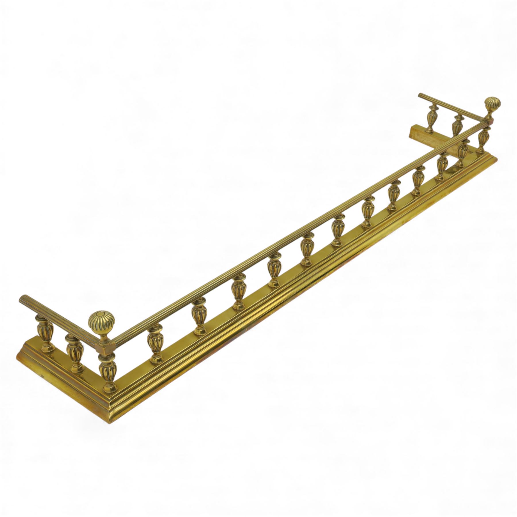 Edwardian brass fire kerb, with reeded and stepped base supporting baluster uprights and reeded top 