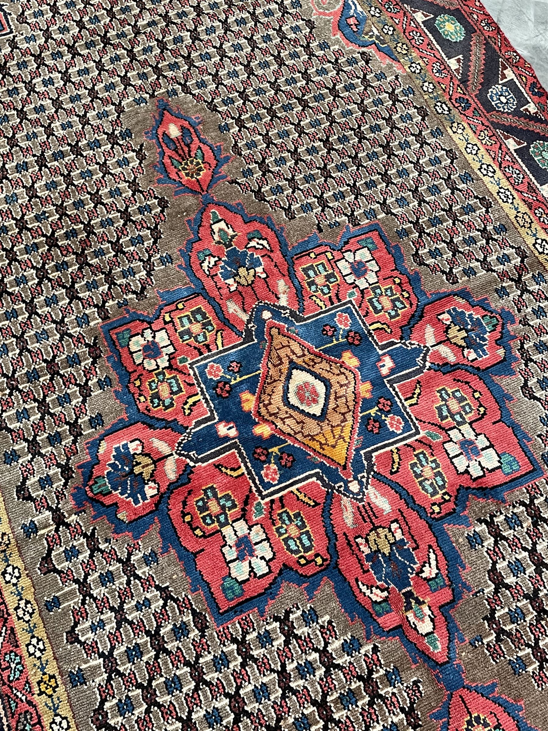 Persian Hamadan rug, the rosette pole medallion on a pale field decorated with stylised motifs, the blue band border decorated with stylised flower heads