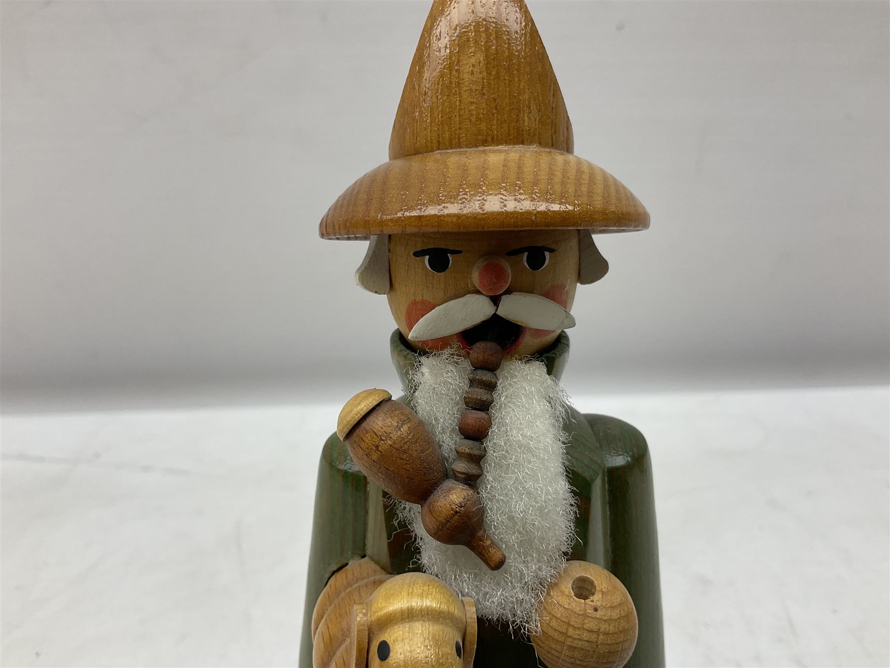 German Erzgebirgische Volkskunst folk art carved and stained wood smoking men incense burner figure, modelled smoking a pipe, with sticker label beneath, H19cm