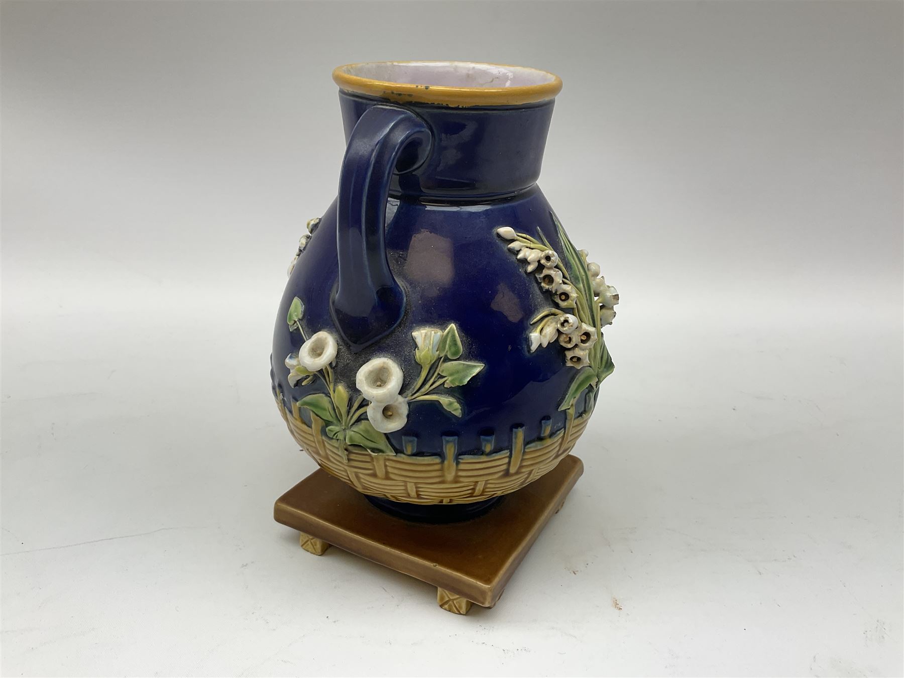 Minton majolica vase, the squat body with twin handles, with part osier moulding and applied Spring flowers against a cobalt blue ground, upon integral square base, impressed beneath Minton 1316, H16.5cm