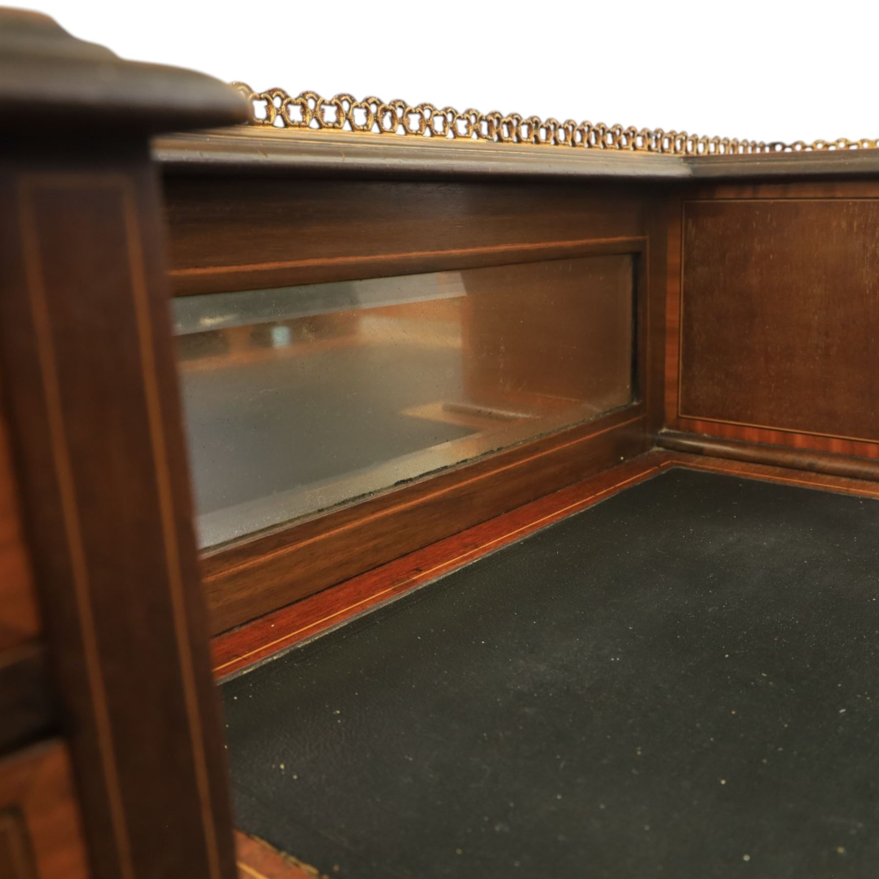 Maple & Co - Edwardian mahogany inlaid writing desk, the superstructure with pierced brass gallery, above an inset mirror and two short drawers, inset leather writing surface, bow fronted with crossbanded drawers and brass swan neck handles, square tapering supports terminating in castors 