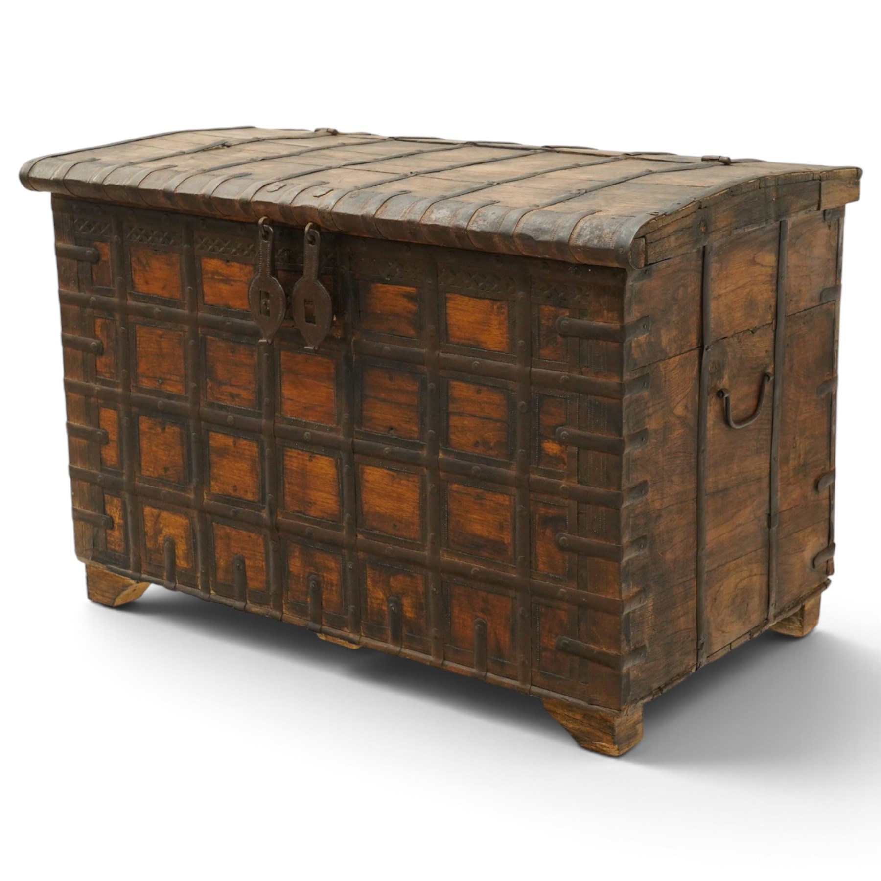 Large 19th century North Indian teak and wrought iron-bound dowry chest, probably Rajasthani, the shallow domed plank lid secured with broad iron straps above a lattice-carved frieze and grid of riveted iron bands, with twin shaped hasps, side carrying handles and fitted interior till, on bracket feet