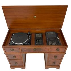Music system in the form of a Georgian design twin pedestal desk, the reed moulded rectangular top hinges to reveal Garrard turntable with Dynatron Amplifier, fitted with speakers enclosed by two doors disguised as drawers, on bracket feet