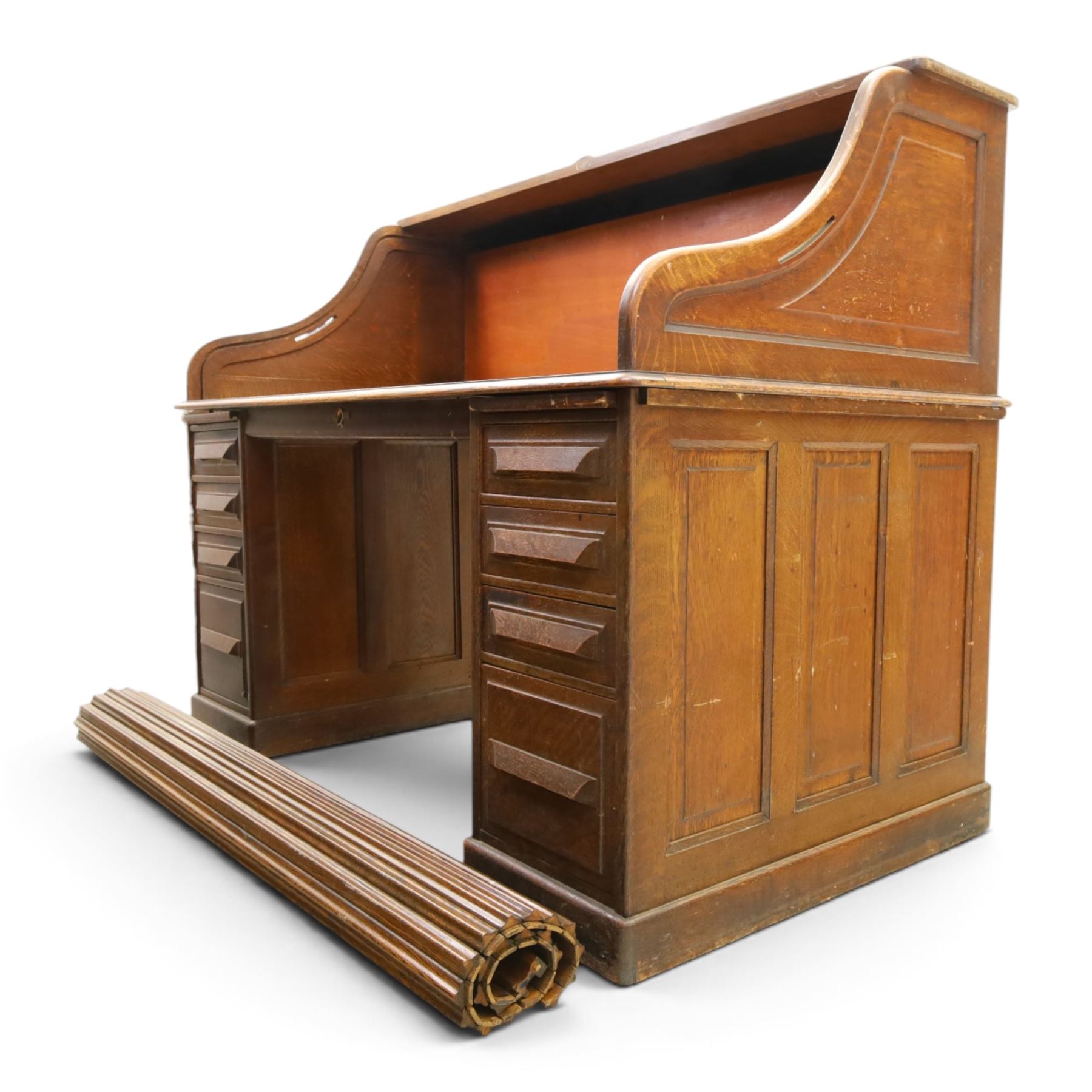 Cutler - Late Victorian oak pedestal tambour desk, the tambour shutter enclosing fitted interior, pull-out writing surface over central kneehole flanked by two pedestals each fitted with four drawers with moulded fronts, pull-out slides above, panelled sides, on moulded plinth base