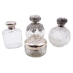 Late Victorian silver mounted glass scent bottle, the body of fluted globular form with pierced scrolling part overlay, and embossed hinged cover lifting to reveal an internal glass stopper, hallmarked Chester 1900, makers mark worn and indistinct, H11.5cm, together with an Edwardian example of similar form, with panelled cut glass body, hallmarked William Neale, Chester 1903, an early 20th century example of facetted oval form, the silver screw threaded cover embossed with a figure amongst blossoming flowers, hallmarked William Comyns & Sons, London 1912, and an early 20th century dressing table jar, the cylindrical octagonal and hobnail cut glass body with silver cover embossed with putti masks, hallmarked S Blanckensee & Son Ltd, Chester, date letter worn and indistinct, D8cm, (4)
