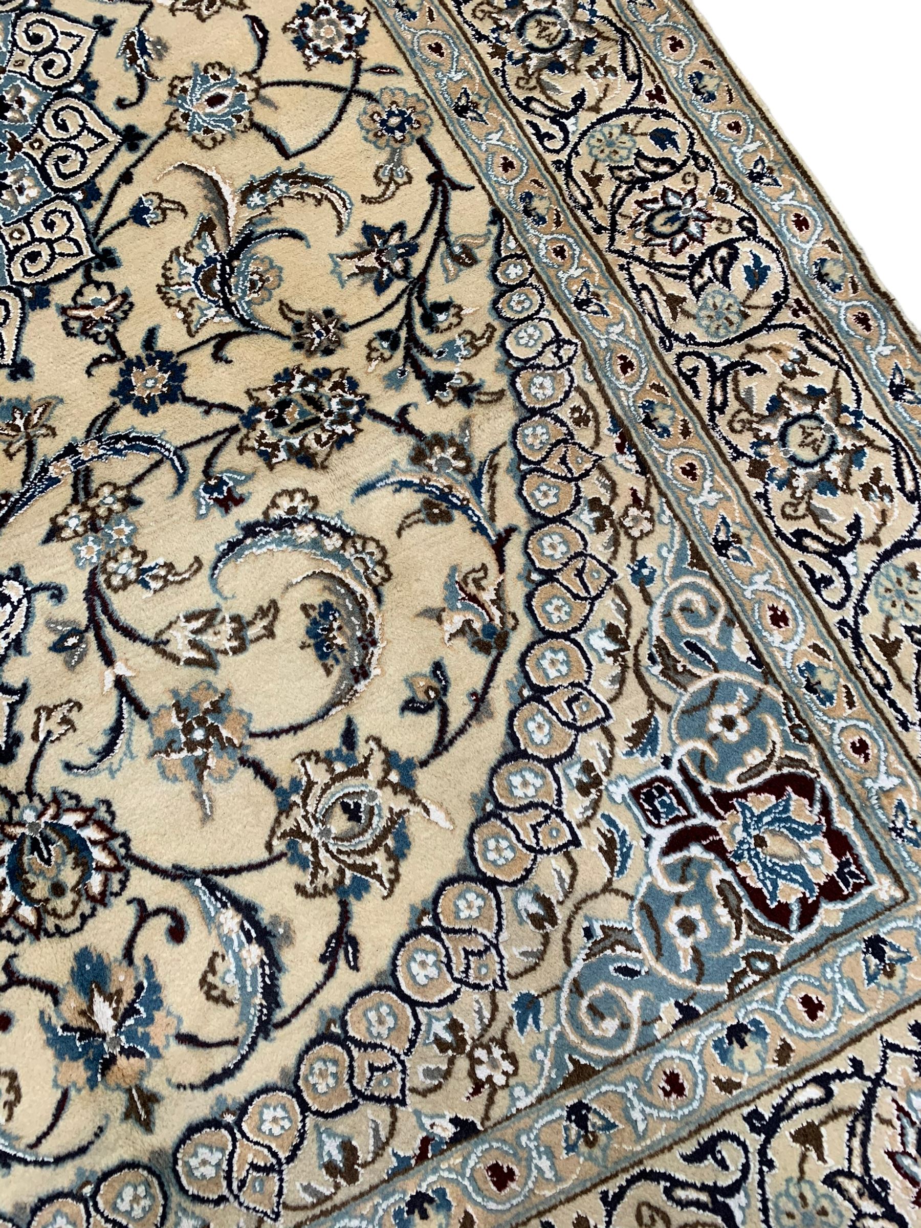 Persian Kashan ivory ground rug, central medallion surrounded by scrolling leafy branches and stylised flowerhead motifs, scrolling border decorated with further stylised plant motifs