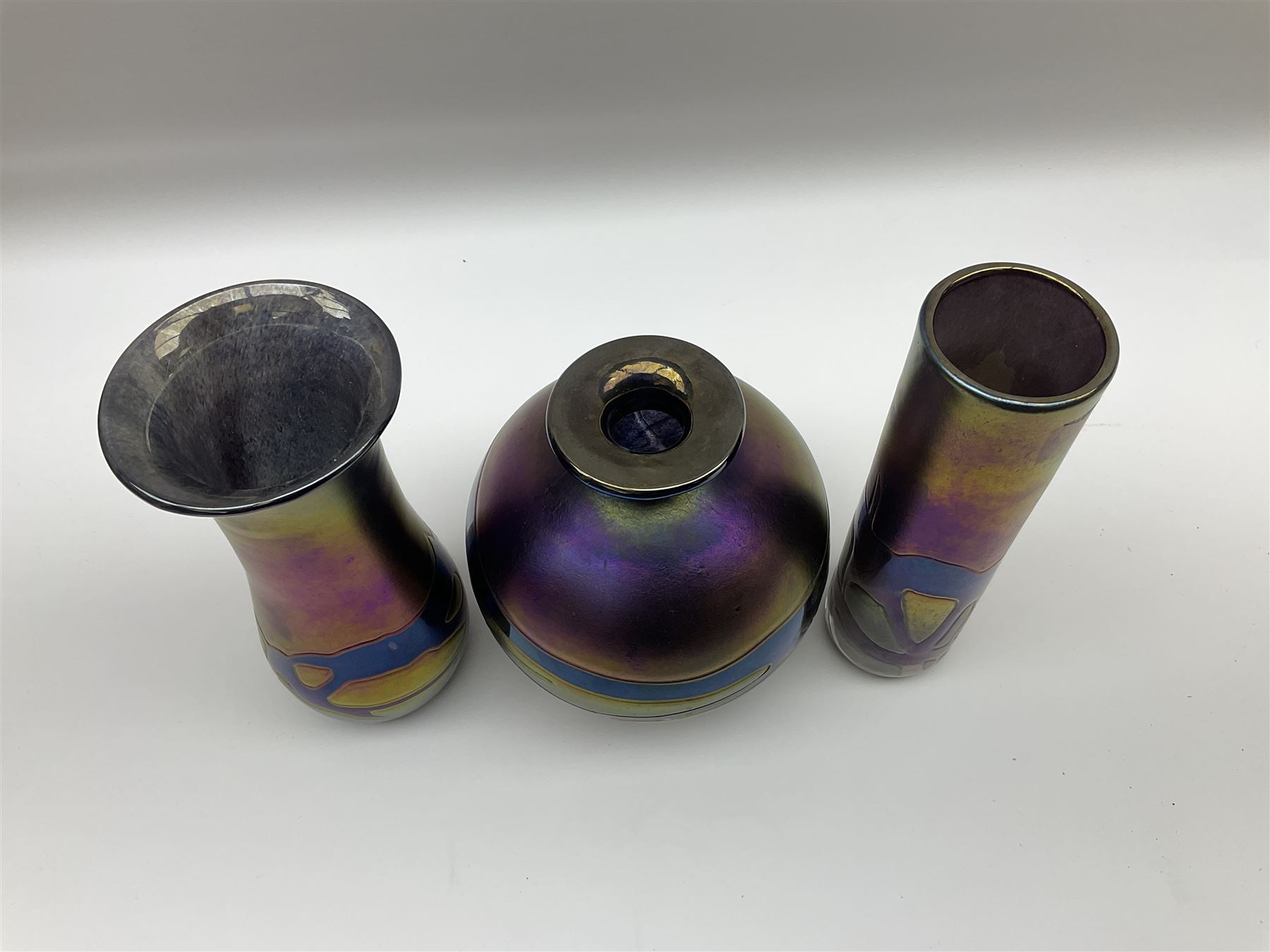 Group of Phoenician Malta art glass vases, all decorated with iridescent amethyst swirl pattern, comprising a spherical example, cylindrical example and baluster shaped example with flared rim, all signed beneath, tallest H20.5cm