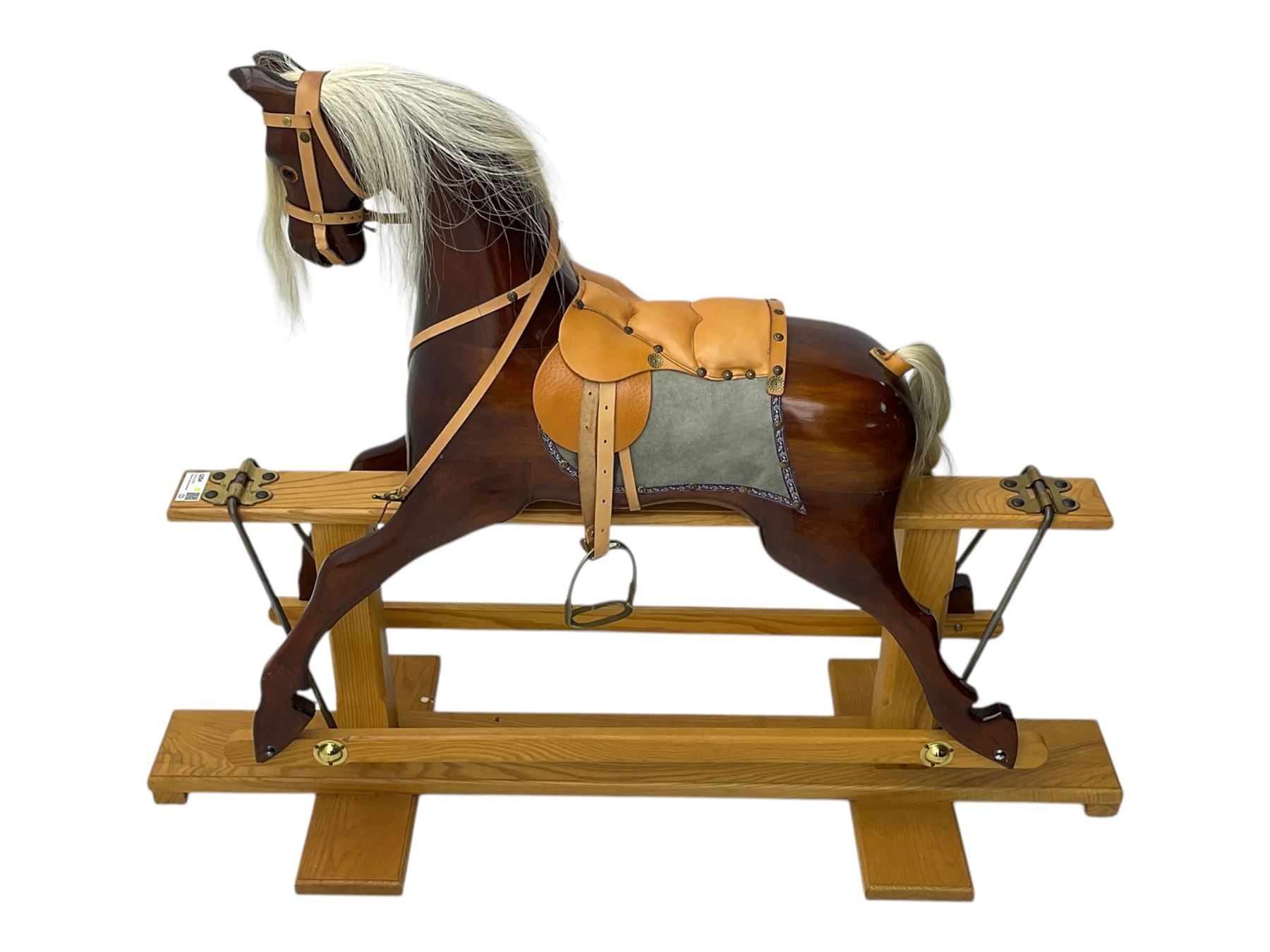 Contemporary carved wooden rocking horse, with leather saddle and bridle, horsehair mane and tail, raised on a pine stand with swing iron supports
