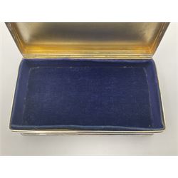 1920's silver table cigarette box, of rectangular form with engine turned decoration to the exterior, the hinged cover with central vacant rectangular panel and raised foliate rim, opening to reveal a gilt interior with later plush lining, hallmarked Charles Henry Dumenil, London 1923, H3.5cm L14.5cm D8.5cm