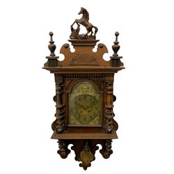 A compact early 20th century German wall clock c1910 in an oak case with applied carvings and decoration, with a brass dial with a chapter written in Arabic's, eight-day spring driven movement striking the hours and half hours on a gong, with visible pendulum beneath.

