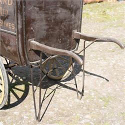 West of England Knitting Co. Ltd. Advertising Hand Cart

A rare and highly decorative late Victorian or Edwardian advertising hand cart, retaining its original black painted finish and gilt signwriting for West of England Knitting Co. Ltd., London, Penzance & St Ives. The enclosed box body is mounted on large cream painted wooden spoked wheels and fitted with rear push handles, allowing the cart to be manoeuvred by hand. Intended as a promotional and delivery vehicle for one of Britain's best known knitwear manufacturers, the cart survives as an evocative piece of commercial advertising history. The interior remains accessible via twin rear doors, while traces of the original maker's transfer for the Warwick Carrier are visible. An unusual and attractive display piece suited to collectors of advertising, transport memorabilia and social history.

Features

• Original hand painted gilt signwriting for West of England Knitting Co. Ltd.
• Advertising panels referencing London, Penzance and St Ives
• Enclosed wooden box body with twin rear access doors
• Original black painted finish with period lettering
• Large cream painted wooden spoked wheels with iron tyres
• Rear push handles for hand propelled operation
• Warwick Carrier maker's transfer remains visible
• Original undercarriage and running gear
• Attractive display piece with strong commercial advertising appeal
• Suitable for museum, retail, interior or collection display

Dimensions:
Overall length: 190 cm
Body length: 125 cm
Overall width: 140 cm
Body width: 100 cm
Height: 150 cm

Wheel Diameter:
Wheels: 92 cm