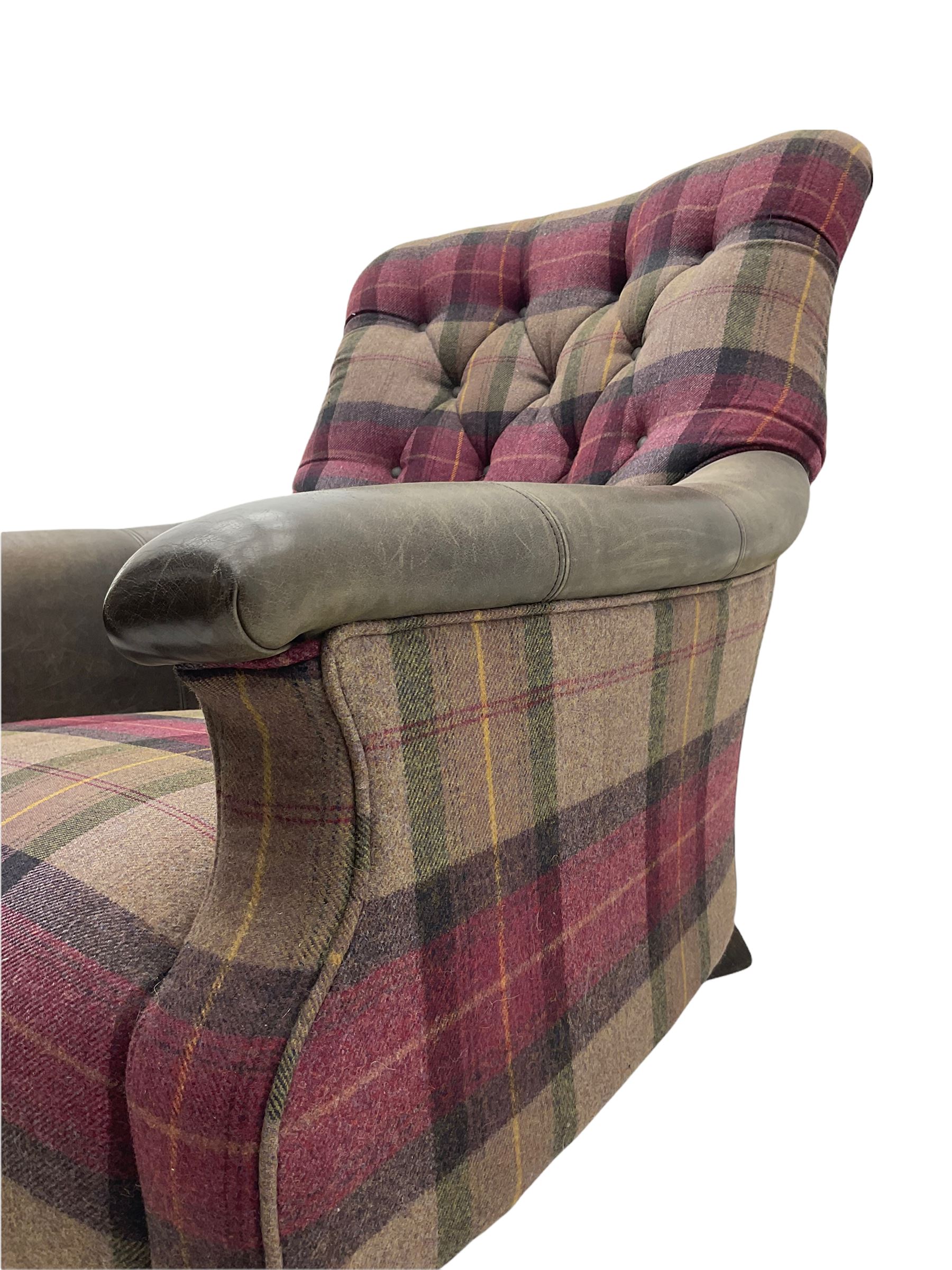 John Sankey - low armchair, buttoned back upholstered in tartan patterned fabric with contrasting grey leather, raised on turned and ebonised front feet with brass and ceramic castors, with matching foot stool