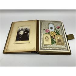 Victorian leather bound musical photo album, the interior leaves containing apertures of various sizes and shapes of portraits surrounded by printed floral designs with lace and cushion detail, with boxed key wound music combination, brass clasp and painted gold decoration to cover and edges