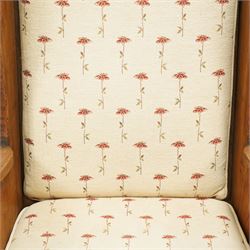 20th century pair of country lambing chairs in light oak, each with high winged back and shaped arms, pegged construction with panelled sides and arched aprons, loose seat and back cushions upholstered in cream floral fabric