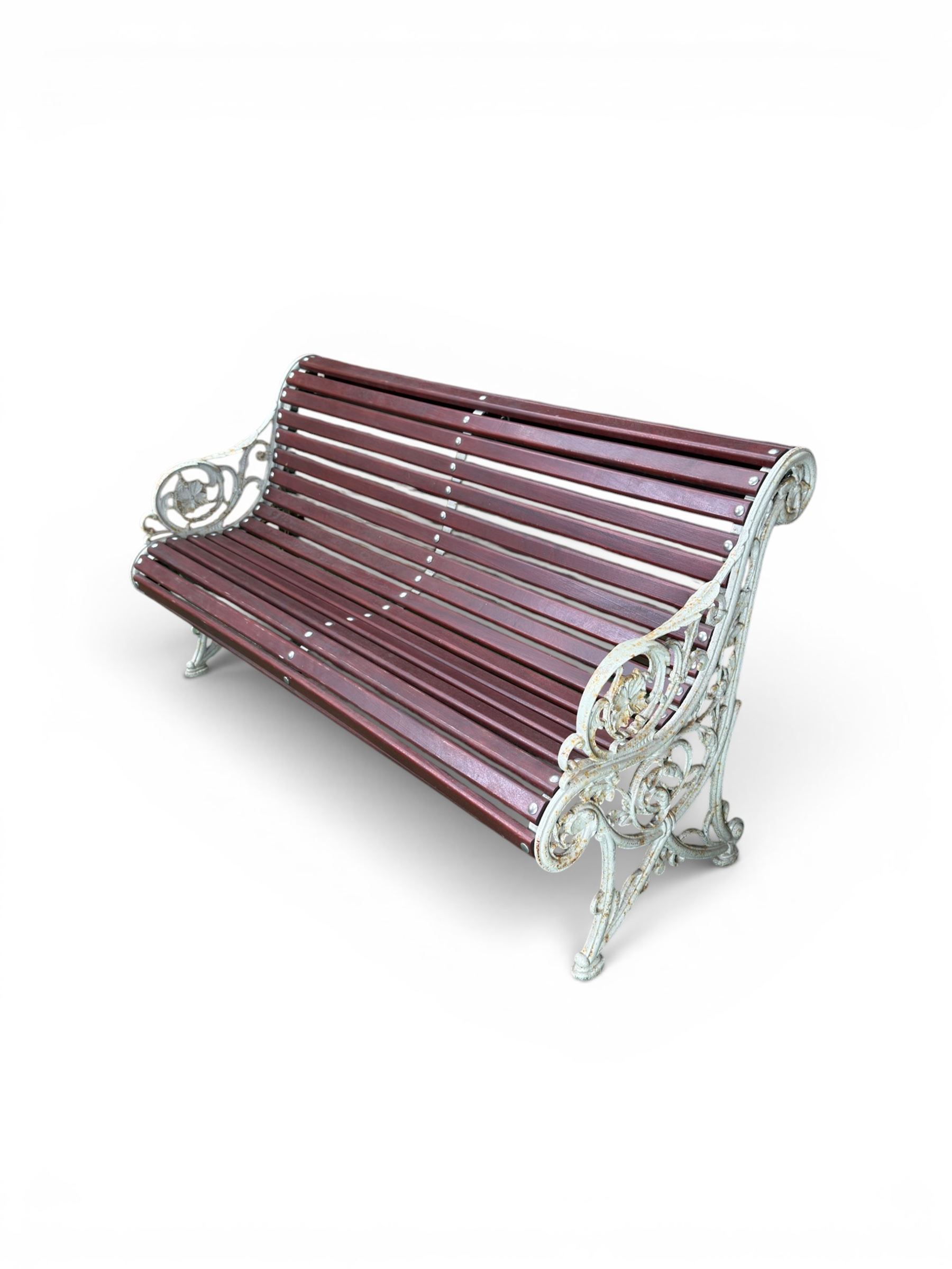 Large late Victorian cast iron garden bench, serpentine form with scroll back and seat, slatted with mahogany stained Sapele