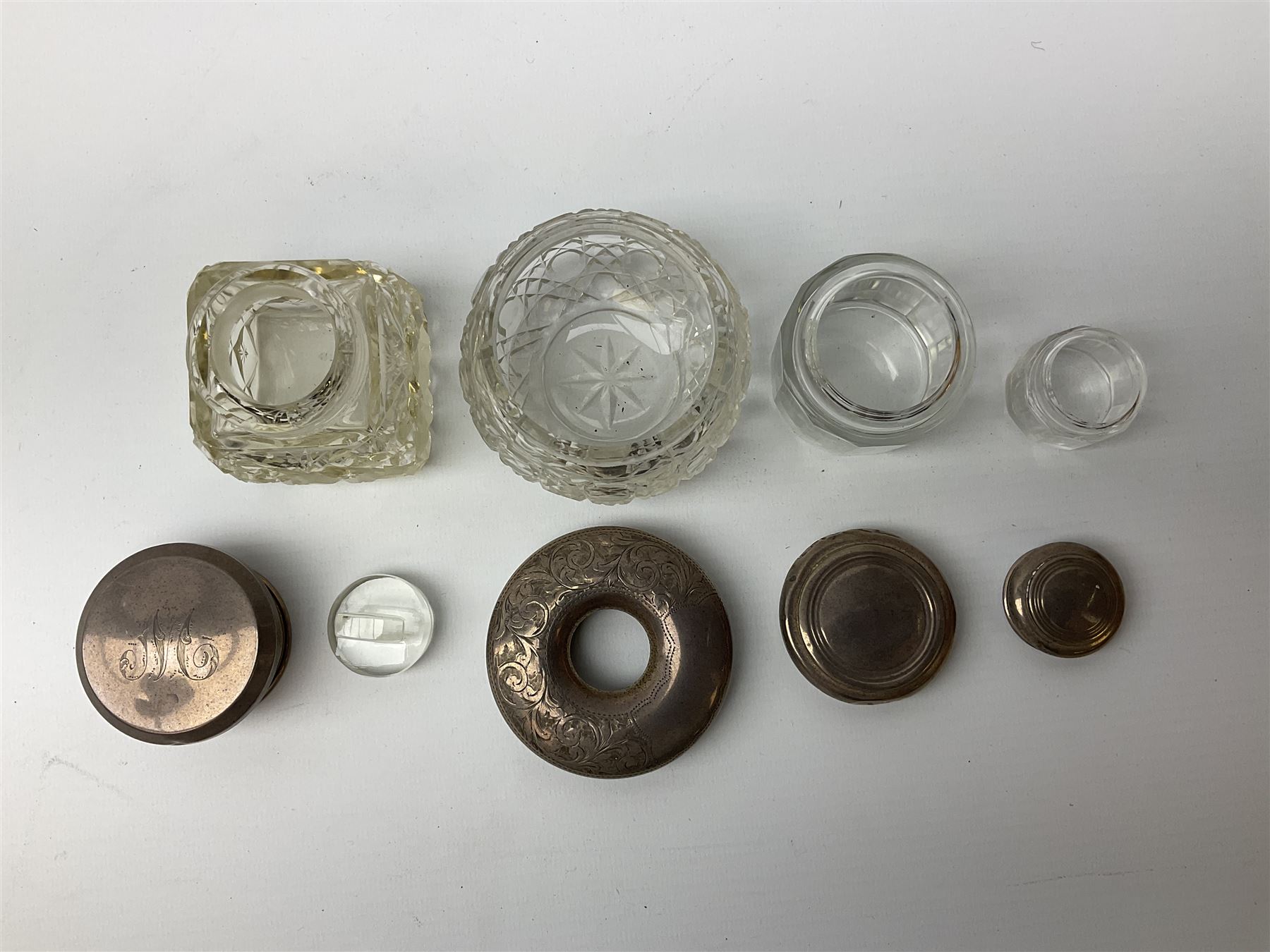 Hallmarked silver top dressing table jars, to include cut glass hobnail example with foliate engraved lid, another 20th century cut glass example with silver engraved screw thread lid, stamped H.S.M Herbert Scott Murdoch, with interior stopper and two smaller glass jars (4)