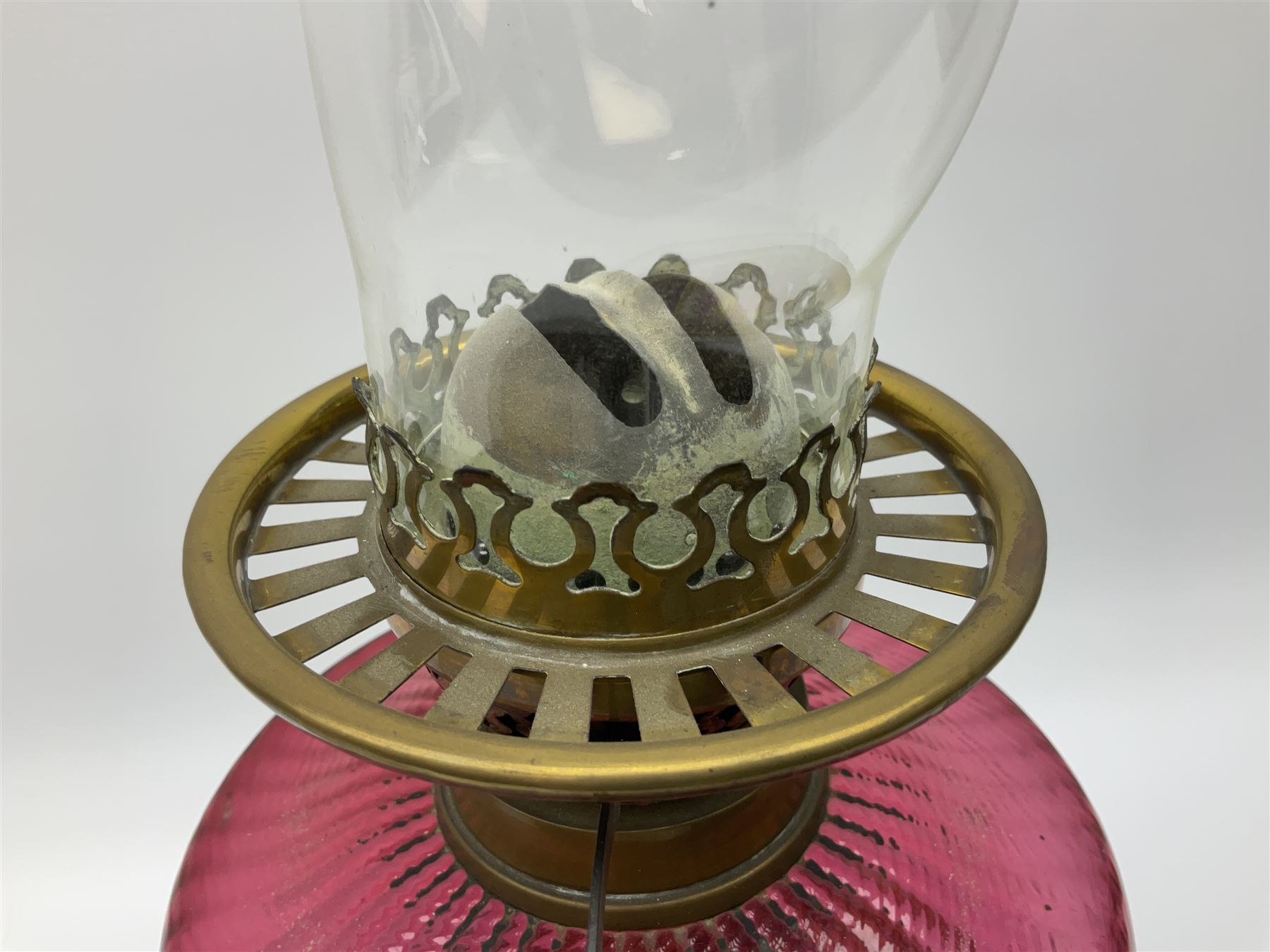Victorian table standing oil lamp, brass fittings, cranberry glass reservoir, brass column on black enamelled ceramic base, with a frosted glass shade and clear glass chimney, H68cm